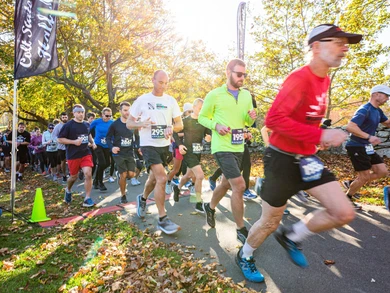 Marathon runners in motion at Colt State Park, surrounded by vibrant fall foliage