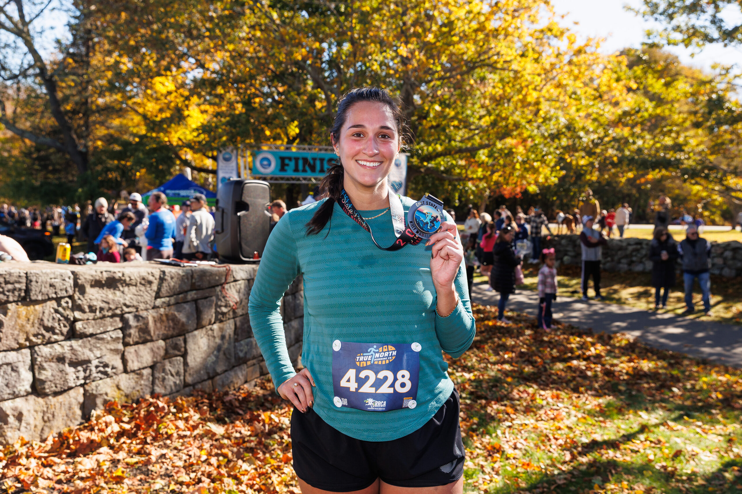 Finisher holding up her medal at the Colt State Park Half Marathon.